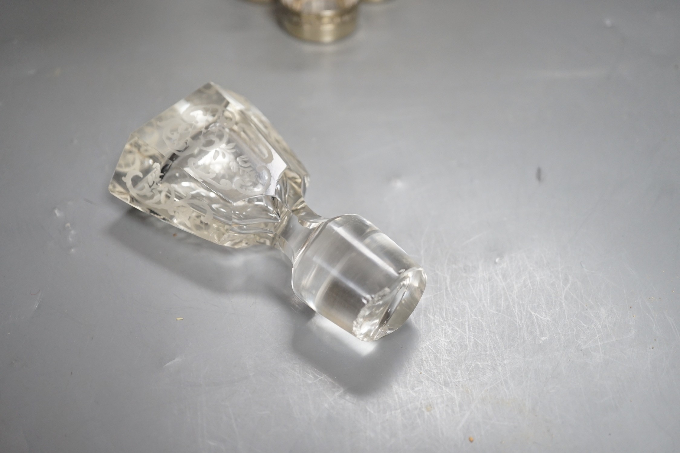 An early 20th century French white metal mounted gilded glass decanter and stopper and four matching tots, decanter height 19.7cm, and a French white metal collared etched glass decanter and stopper.